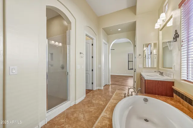 a spacious bathroom with a tub sink and mirror