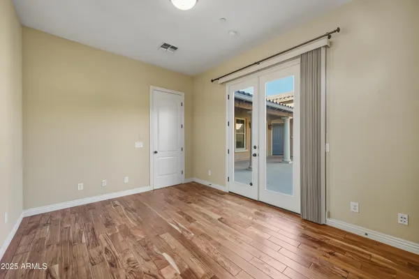 a view of an empty room with wooden floor and closet