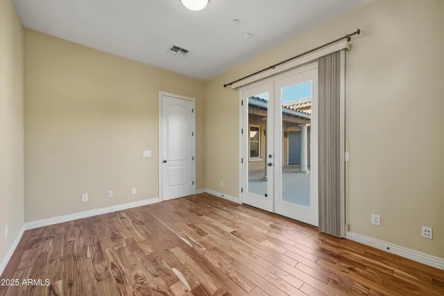 a view of an empty room with wooden floor and closet