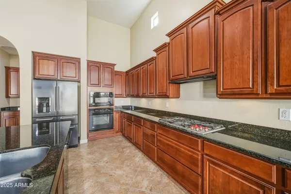 a kitchen with stainless steel appliances granite countertop a refrigerator a stove and a sink