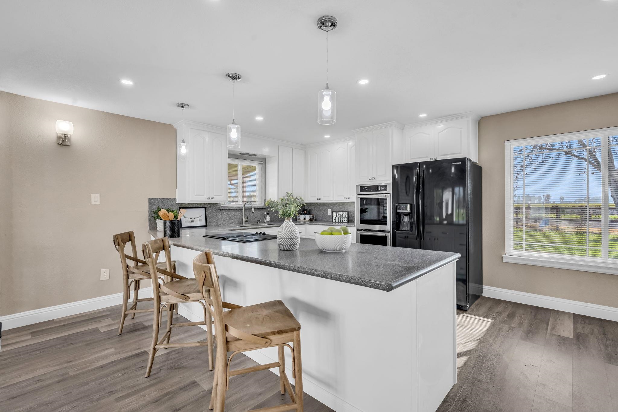 1660 Sunset Road Brentwood, CA 94513 - Photo 12 of 45 Kitchen with black appliances, white cabinetry, pendant lighting, a kitchen breakfast bar, and backsplash