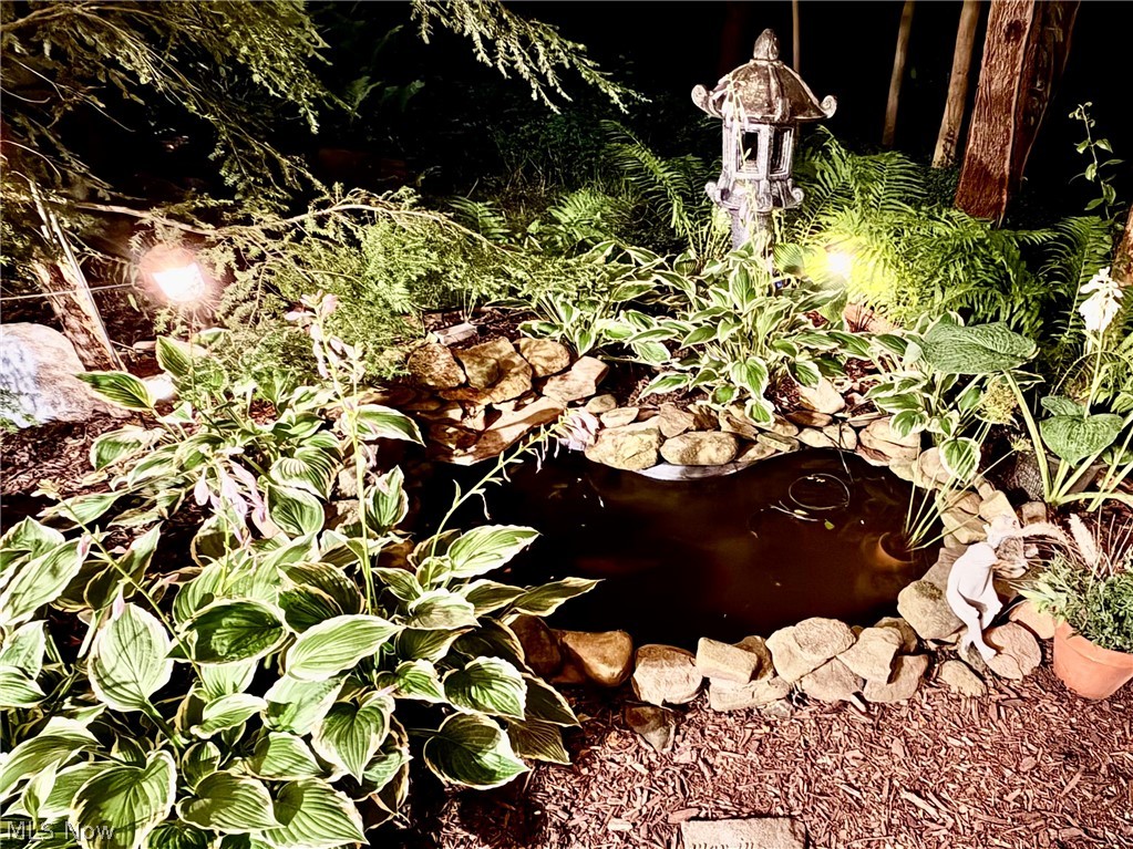 171 Granger Road, Unit 107 Medina, OH 44256 - Photo 40 of 41 Landscaped garden pond featuring a stone border, an ornamental pagoda lantern, diverse plant foliage, and integrated accent lighting