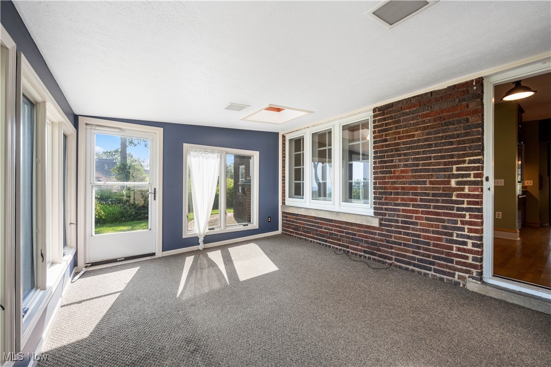 24510 Lake Road Bay Village, OH 44140 - Photo 31 of 45 Unfurnished sunroom with brick wall, carpet, healthy amount of natural light, and a textured ceiling