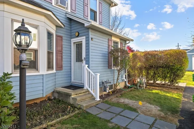 a view of a house with brick walls plants and large tree