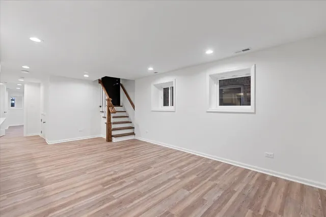 a view of an empty room with wooden floor and stairs