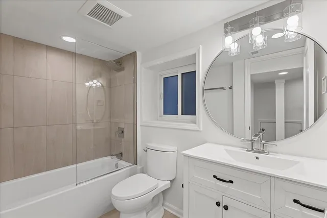 a bathroom with a toilet a sink a mirror a bathtub and vanity