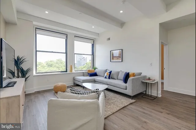a living room with furniture large window and wooden floor