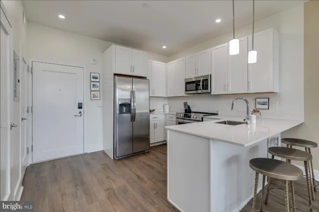 a kitchen with stainless steel appliances granite countertop a refrigerator a sink a stove a microwave and a refrigerator with wooden floor