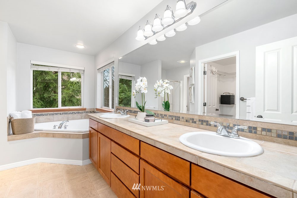 17813 20th Avenue Southeast, Unit 57 Bothell, WA 98012 - Photo 16 of 25 a bathroom with a granite countertop sink a large mirror and a bathtub next to a window
