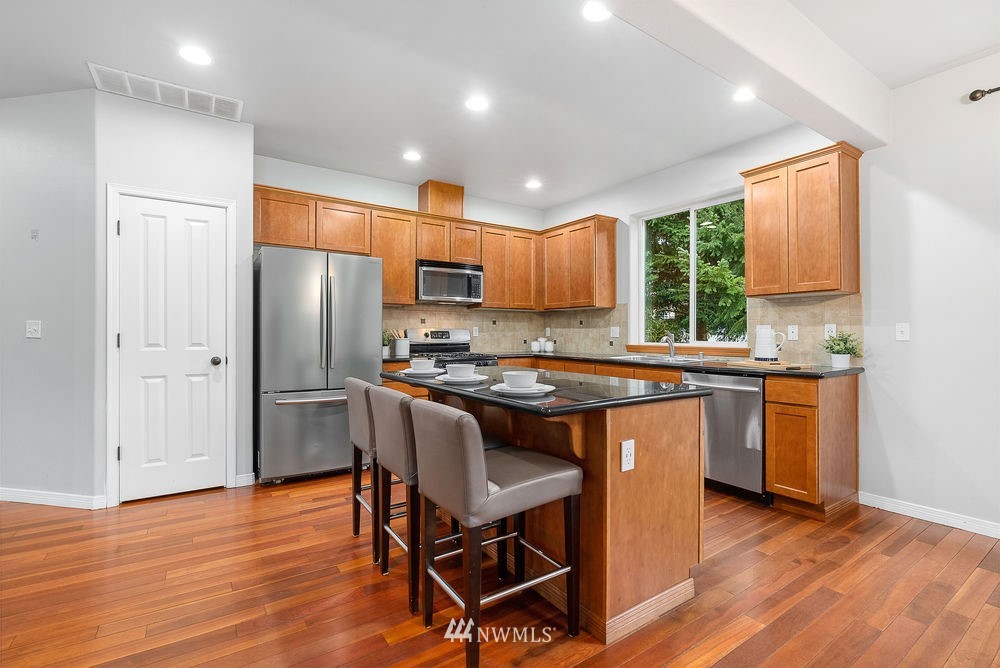 17813 20th Avenue Southeast, Unit 57 Bothell, WA 98012 - Photo 8 of 25 a kitchen with stainless steel appliances granite countertop a refrigerator a stove top oven a sink dishwasher and a dining table with wooden floor