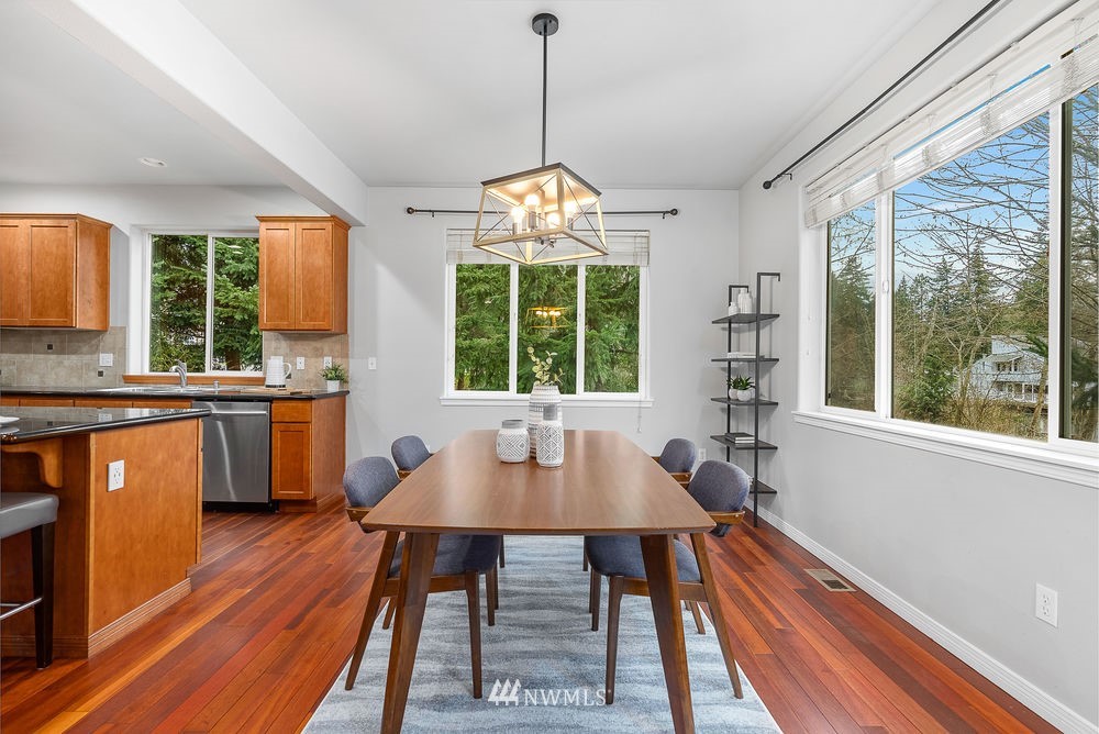 17813 20th Avenue Southeast, Unit 57 Bothell, WA 98012 - Photo 9 of 25 a dining room with wooden floor a chandelier a wooden table and chairs
