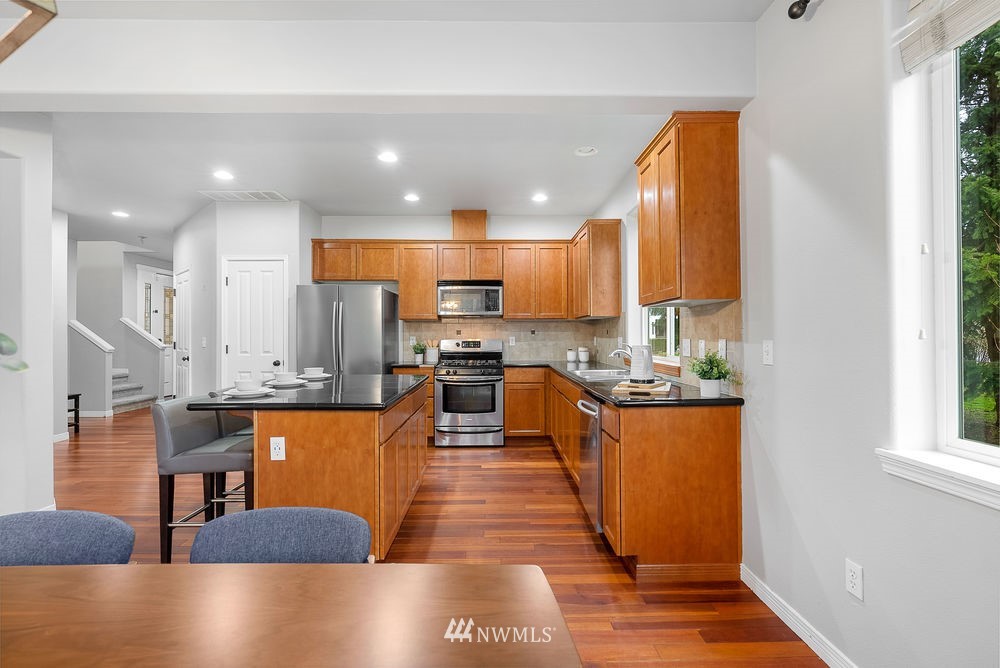 17813 20th Avenue Southeast, Unit 57 Bothell, WA 98012 - Photo 10 of 25 a large kitchen with stainless steel appliances granite countertop a stove a sink a refrigerator and white cabinets with wooden floor