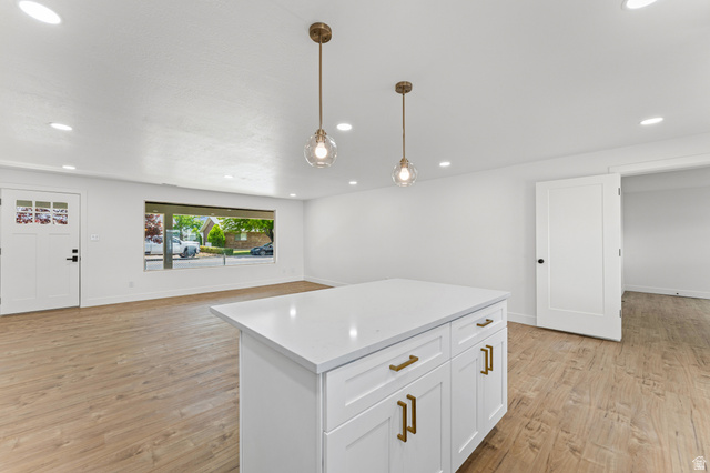 1898 West 600 South Provo, UT 84601 - Photo 8 of 32 Open-concept area featuring a kitchen island with a white countertop and brass hardware, wood-finish flooring, two pendant light fixtures, and recessed ceiling lighting