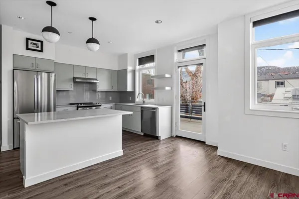 a kitchen with stainless steel appliances granite countertop a refrigerator a stove a sink dishwasher a oven with white cabinets and wooden floor