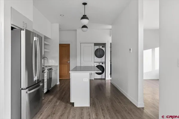 a view of a kitchen with a refrigerator and wooden floor