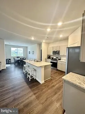 a large white kitchen with lots of counter space a sink a appliances and living room view
