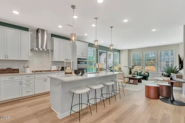 a kitchen with stainless steel appliances granite countertop a stove top oven a sink dishwasher a dining table and chairs with wooden floor