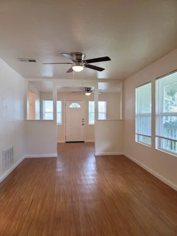 a view of an empty room with wooden floor and a window