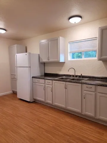 a kitchen with granite countertop a refrigerator and a sink