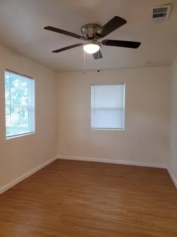 a view of an empty room with a window and wooden floor