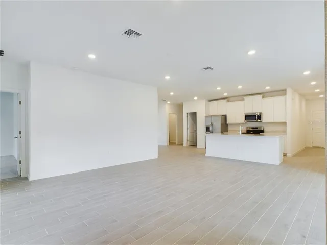 a view of kitchen with kitchen island refrigerator sink and a stove with wooden floor