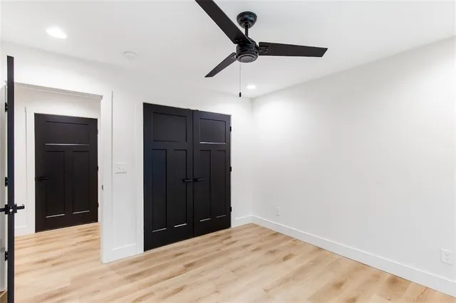 an empty room with wooden floor ceiling fan and windows
