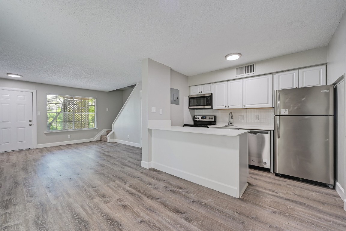 1200 Banister Lane, Unit 5 Austin, TX 78704 - Photo 1 of 13 a kitchen with a refrigerator a stove top oven and white wooden cabinets