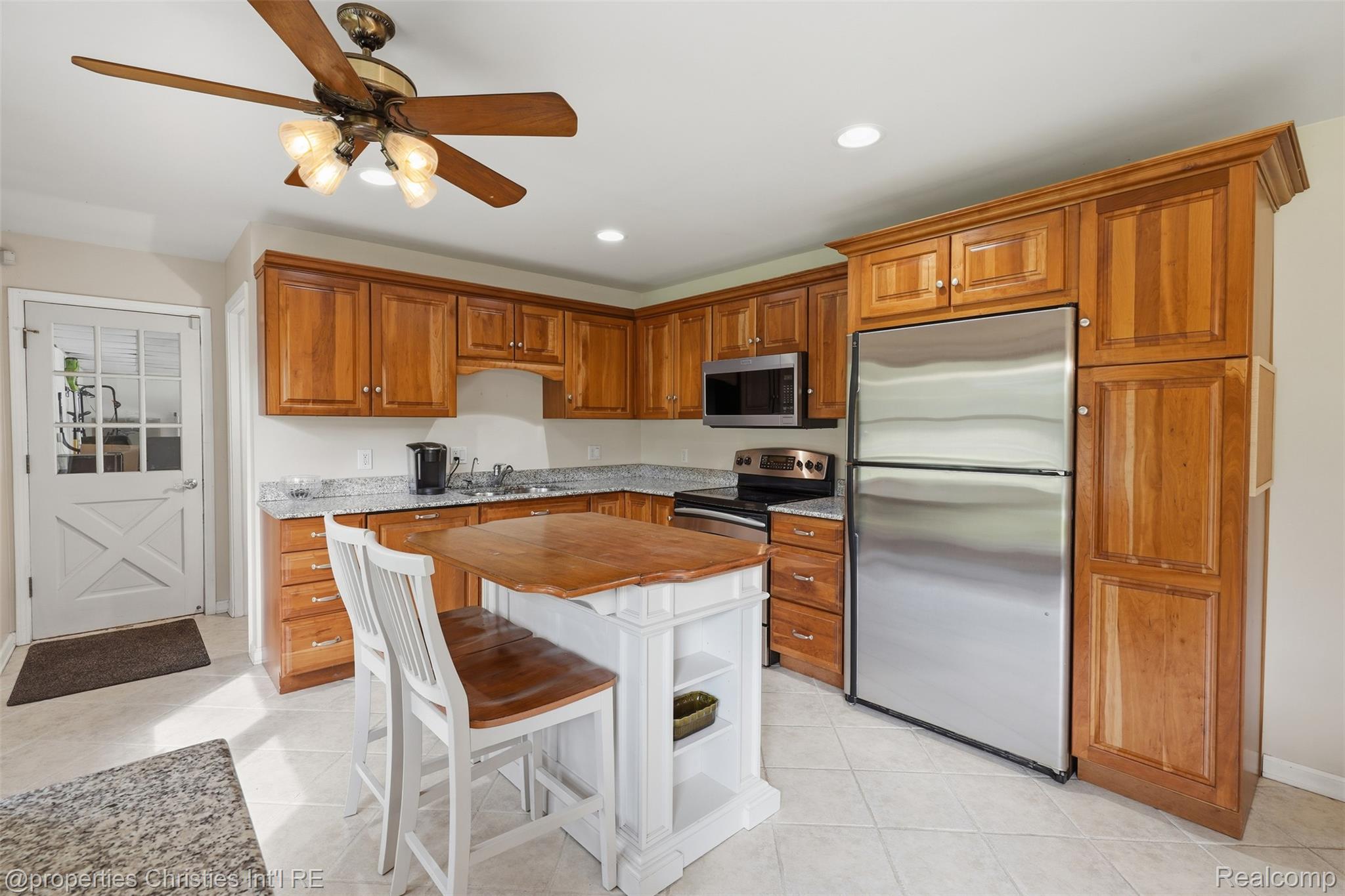 4030 Textile Road Ypsilanti, MI 48197 - Photo 13 of 58 Wood cabinetry with stone countertops, stainless steel appliances, kitchen island, ceiling fan, and tiled flooring