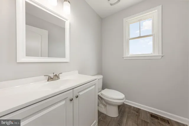 a bathroom with a toilet sink vanity and mirror