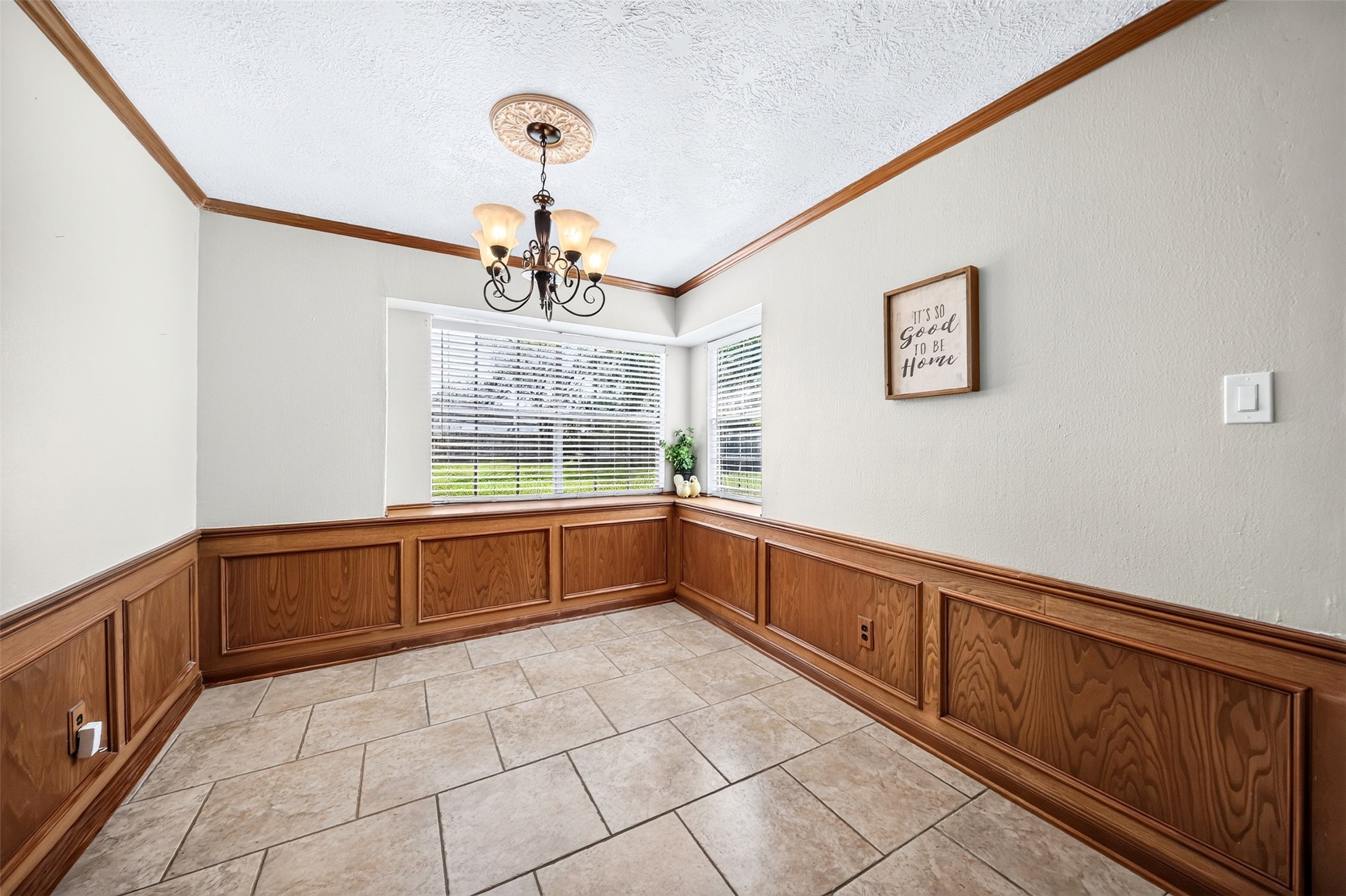 6507 Spring Leaf Drive Spring, TX 77379 - Photo 13 of 50 Bright breakfast area with classic wood paneling, crown molding, large windows, decorative chandelier, and durable tile flooring-an inviting space for everyday dining.