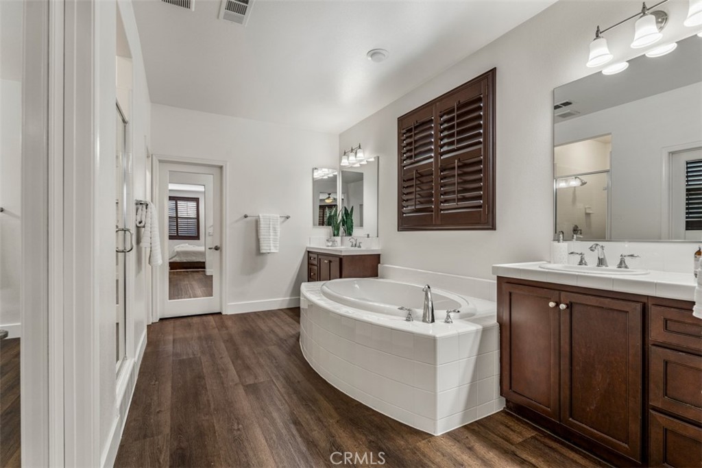 14977 Brooktree Street Eastvale, CA 92880 - Photo 11 of 34 a spacious bathroom with a double vanity sink a mirror and a bathtub