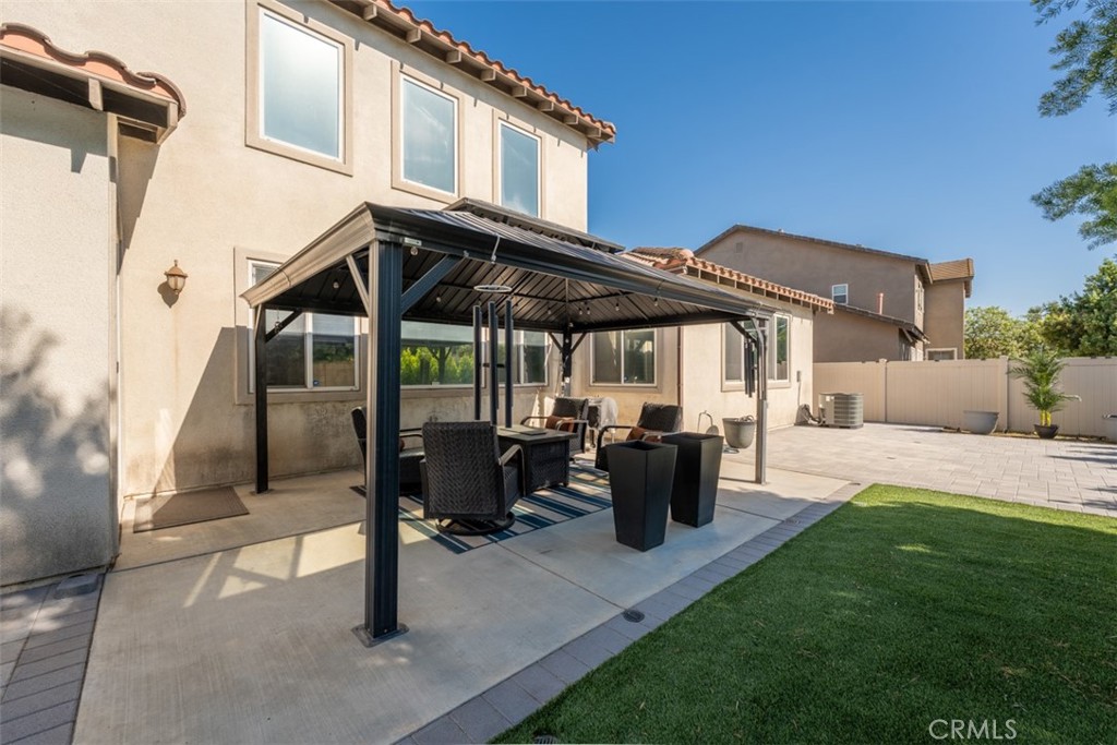 14977 Brooktree Street Eastvale, CA 92880 - Photo 21 of 34 a view of a patio with table and chairs under an umbrella with a barbeque grill and plants