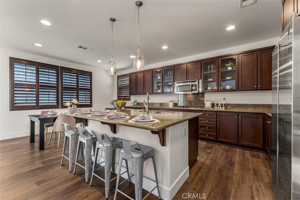 14977 Brooktree Street Eastvale, CA 92880 - Photo 5 of 34 a kitchen with lots of counter top space a sink appliances and cabinets