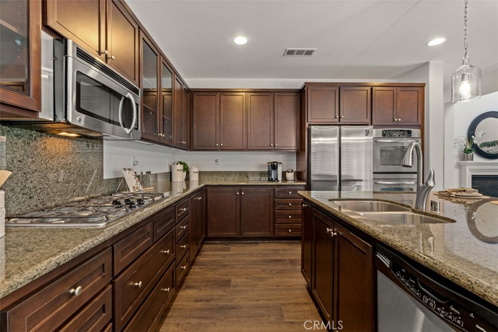 14977 Brooktree Street Eastvale, CA 92880 - Photo 7 of 34 a kitchen with stainless steel appliances granite countertop a sink stove and refrigerator