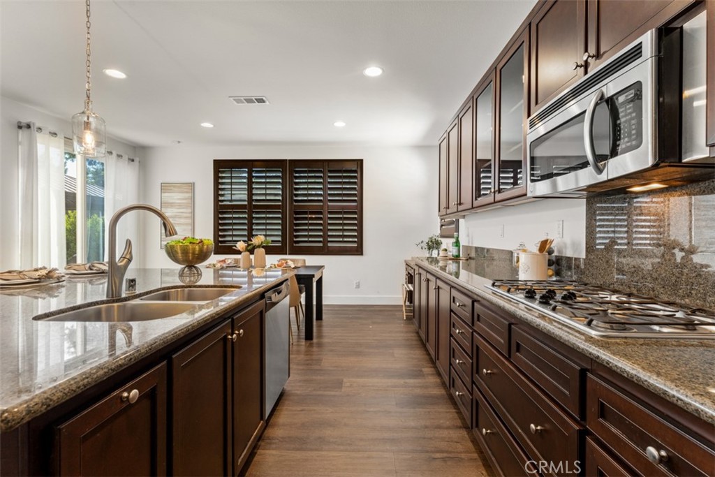 14977 Brooktree Street Eastvale, CA 92880 - Photo 8 of 34 a kitchen with stainless steel appliances a sink stove and cabinets