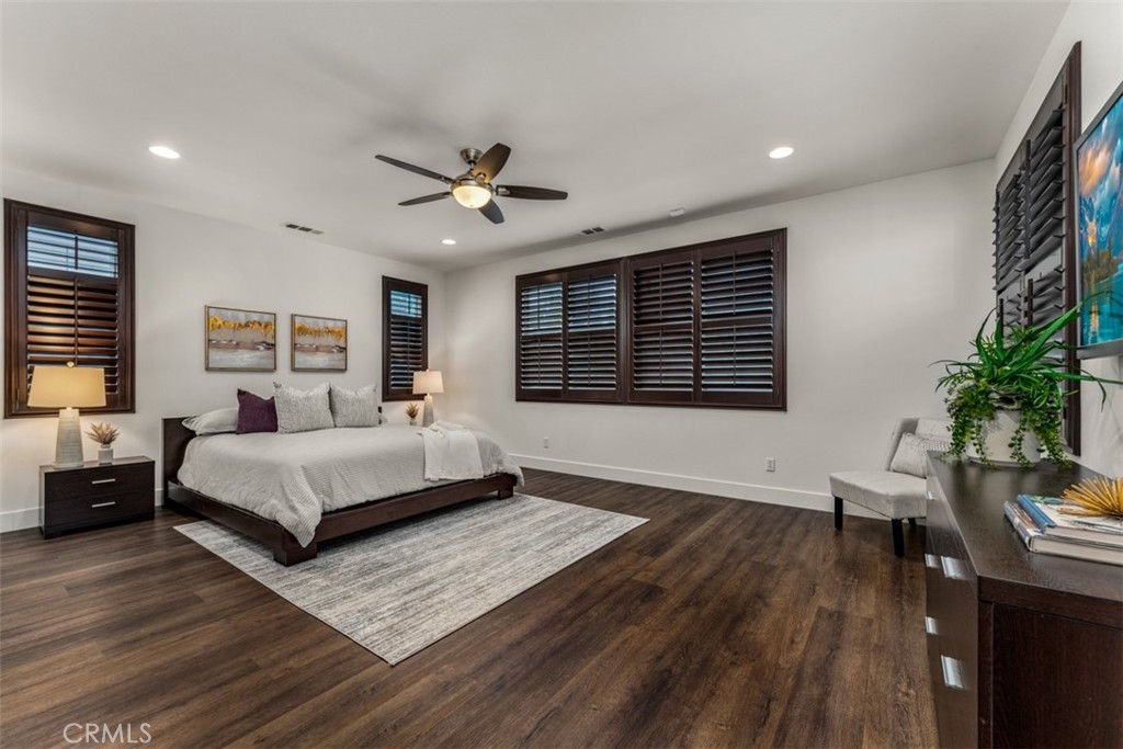 14977 Brooktree Street Eastvale, CA 92880 - Photo 10 of 34 a spacious bedroom with a large bed a chandelier and windows