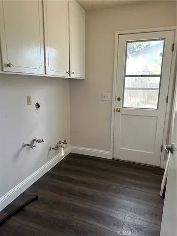a view of an empty room with wooden floor and cabinets
