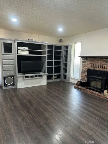 an empty room with wooden floor fireplace and a window
