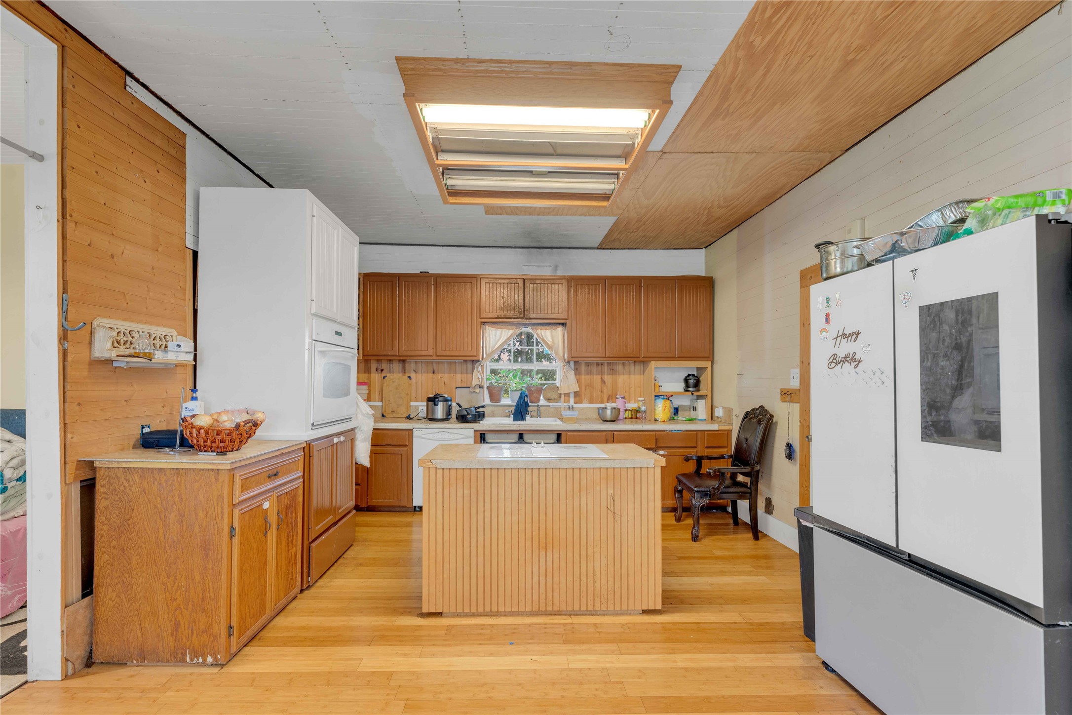 20235 Engelmann Lane Manor, TX 78653 - Photo 22 of 34 Kitchen featuring wooden walls, white appliances, light countertops, light wood-style floors, and a kitchen island