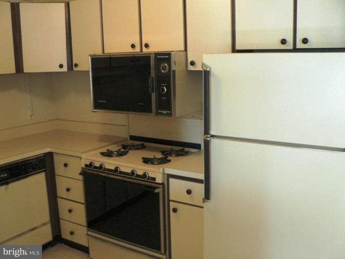 1111 University Boulevard West, Unit 413A Silver Spring, MD 20902 - Photo 10 of 14 a kitchen with a stove and a refrigerator