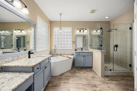 a spacious bathroom with a granite countertop tub sink shower and mirror