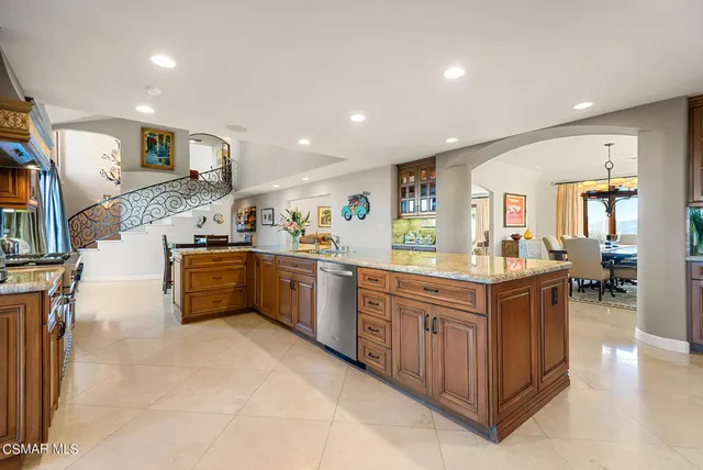 a kitchen with stainless steel appliances kitchen island granite countertop a stove a sink a refrigerator and a dining table