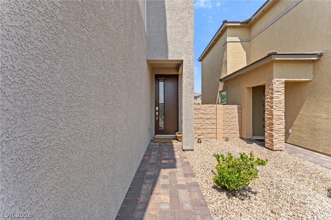 8879 Roadrunner Ravine Street Las Vegas, NV 89166 - Photo 2 of 39 A welcoming entry path leads to a contemporary home, boasting stucco and stone details amidst a low-maintenance landscape.