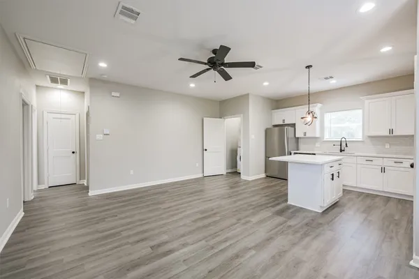 a large white kitchen with a refrigerator a sink dishwasher a stove and white cabinets with wooden floor