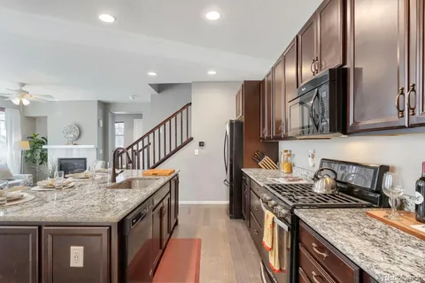 a kitchen with granite countertop stainless steel appliances a sink a stove top oven a counter space and cabinets