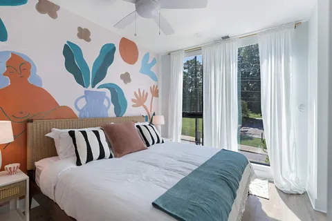 a bedroom with a bed and a flat tv screen on wall