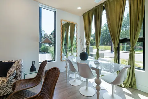 a dining room with furniture and large windows