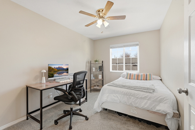 99 Penhurst Place Logan, UT 84341 - Photo 19 of 34 Neutral tone wall paint, textured carpeting, a multi-pane window with blinds, and a brass-finish ceiling fan with lighting