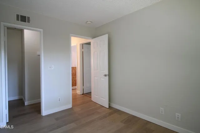 a view of an empty room with wooden floor and closet