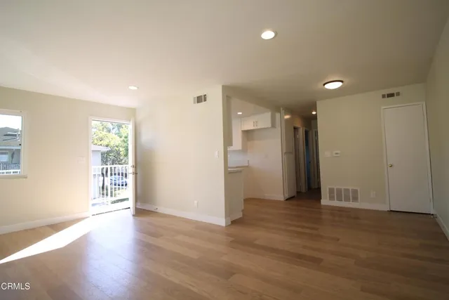 a view of an empty room with wooden floor and a window